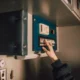 Persona cargando un lavavajillas moderno con la puerta abierta y ajustando el panel de control, imagen para el artículo Lavavajillas Candy Rapido: instrucciones en español y claves de uso
