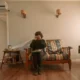Aire acondicionado portátil con tubo: guía clara para elegir bien — unidad portátil colocada junto a la ventana con tubo de escape y una persona ajustando el termostato en una sala moderna.