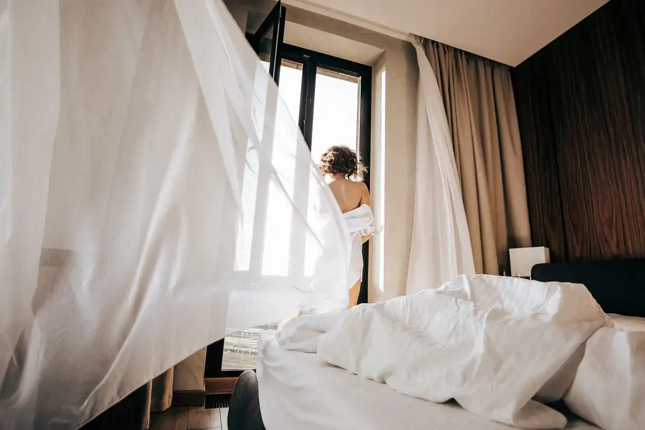 Climatizador evaporativo portátil junto a una cama, una imagen que explica cómo funciona el aire acondicionado portatil sin tubo exterior.