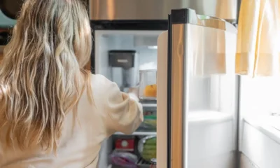 Técnico revisando un frigorífico averiado por fuga de gas frigorífico síntomas en una cocina doméstica