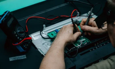 Técnico comprobando el termostato frigorífico balay no frost con un multímetro mientras repara un frigorífico abierto.