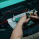 Técnico comprobando el termostato frigorífico balay no frost con un multímetro mientras repara un frigorífico abierto.