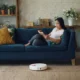 Robot aspirador autovaciado sin bolsa: guía para elegir bien — robot aspirador sin bolsa regresando a su estación de vaciado en un salón moderno junto al sofá.
