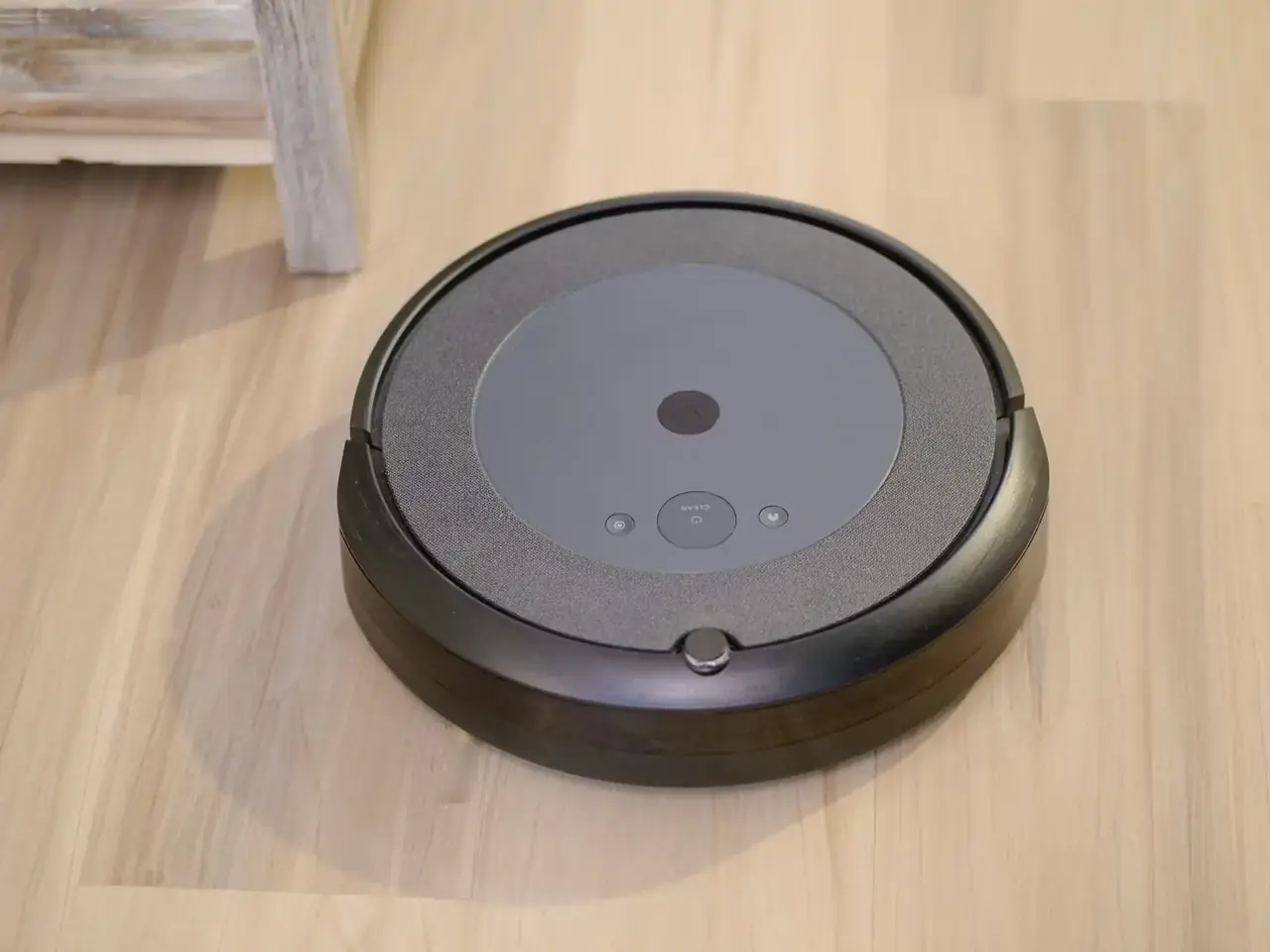 Robot aspirador rowenta explorer serie 60 animal care connect limpiando debajo de un sofá bajo en un salón con mascota.