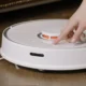 Robot aspirador blanco bajo un sofá, ideal para ilustrar el análisis del lefant m330 pro robot aspirador y su capacidad para limpiar debajo de los muebles.