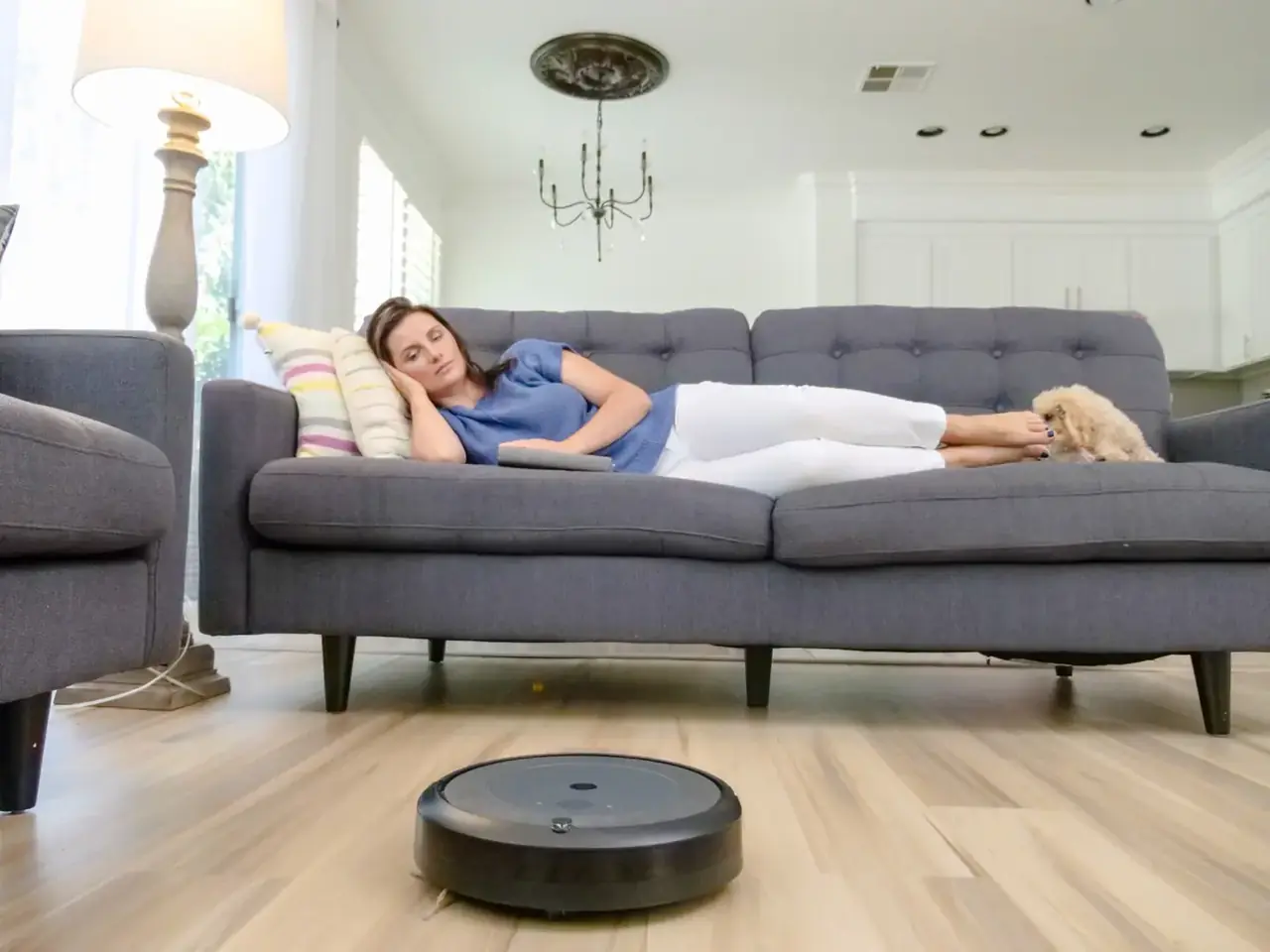 Robot aspirador para mascotas: opiniones, precios y claves 2026 — robot aspirador limpiando pelo de mascota en un salón moderno con suelo de madera y un perro descansando al lado, ilustrando su uso en hogares con animales.