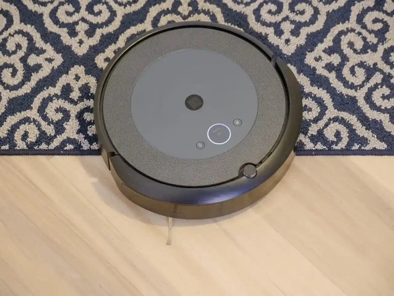 El robot que limpia varias plantas ya puede subir escaleras: robot aspiradora con diseño compacto subiendo una escalera de madera en una casa moderna.