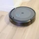 Foto de un aspirador robot irobot roomba 105 combo limpiando el suelo duro junto a un sofá en un salón moderno.