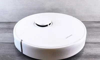Aspirador robot Dreame L10s Ultra Gen 2 reviews: un robot aspirador blanco limpiando el suelo de una casa moderna junto a su estación de carga