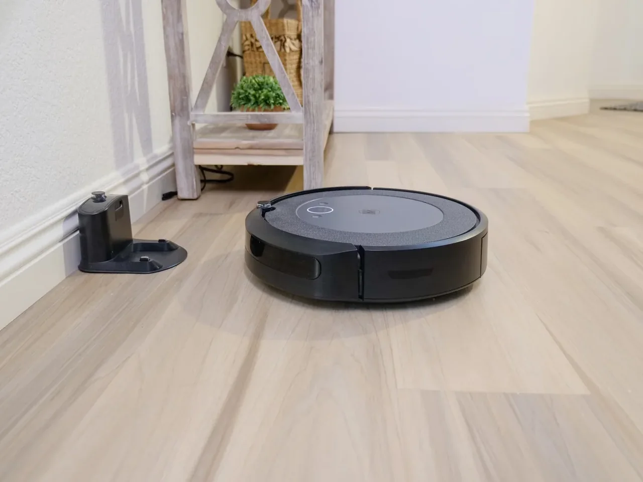 Robot aspirador autovaciado sin bolsa en un salón moderno junto a su base de carga