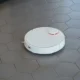 Fotografía que ilustra la evolución electrodomésticos limpieza: robot aspirador moderno en el suelo junto a una escoba antigua