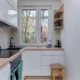 Cocina de un piso pequeño con electrodomesticos compactos para pisos pequeños y una persona cocinando