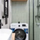 Mini lavadora con vapor en un rincón de apartamento pequeño, ideal para espacios reducidos.