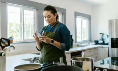 Cocina inteligente con electrodomésticos del futuro conectados a una app, destacando control por teléfono.