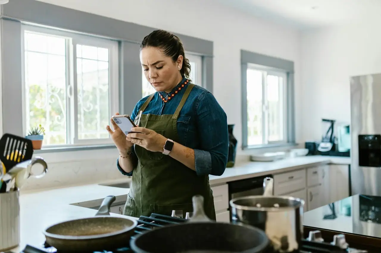Cocina inteligente con electrodomésticos del futuro conectados a una app, destacando control por teléfono.
