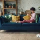 Robot aspirador en un salón moderno limpiando suelo de madera mientras una persona lo controla con el móvil — imagen para 'Qué robot aspirador comprar en 2025: guía con claves reales'