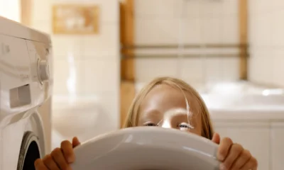 Persona usando el móvil para conectar lavadora a google home en una lavandería moderna con lavadora inteligente