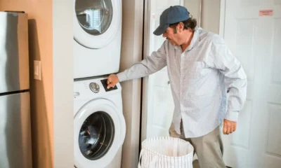 Lavadora y secadora en torre: guía para ganar espacio y comodidad — lavadero compacto con lavadora y secadora apiladas, estanterías organizadas y una persona colocando ropa.