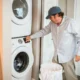 Lavadora y secadora en torre: guía para ganar espacio y comodidad — lavadero compacto con lavadora y secadora apiladas, estanterías organizadas y una persona colocando ropa.
