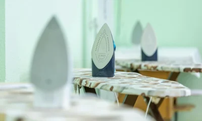 Imagen de una plancha sobre una tabla de planchar con vapor, adecuada para ilustrar limpiar y desinfectar plancha.