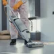Técnico limpiando un filtro de un conducto de aire acondicionado con una aspiradora y guantes — Cómo limpiar filtros aire acondicionado por conductos sin dañarlos