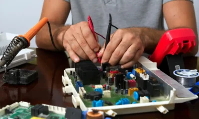 Técnico inspeccionando la unidad interior de un aire acondicionado con la carcasa abierta y las partes visibles — Partes de un aire acondicionado: guía clara y completa
