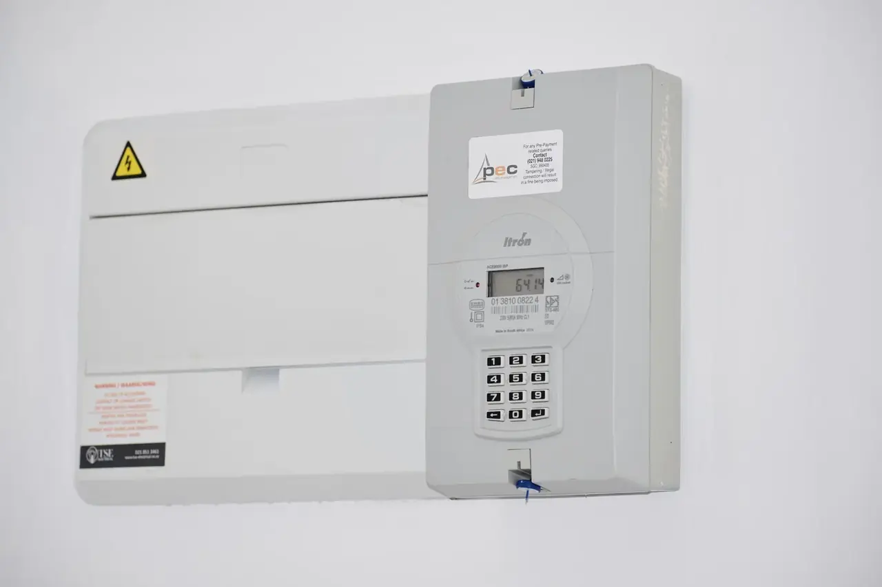 Técnico usando una pinza amperimétrica junto a un split de pared, imagen práctica sobre cuantos watts consume un aire acondicionado de 3000 frigorías inverter.