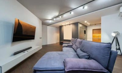 Técnico instalando un televisor en un soporte de pared para televisores: guía para elegir bien, con taladro y detector de montantes en un salón moderno.