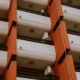 Técnico quitando un aparato de aire acondicionado de un balcón con el edificio de viviendas de fondo — imagen para ilustrar 'Me pueden obligar a quitar el aire acondicionado: cuándo procede'.