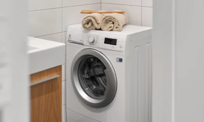 Lavadora carga superior Hoover medidas en una lavandería estrecha con cinta métrica y espacio reducido para comprobar el ajuste