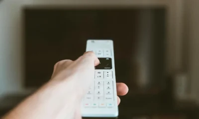 Un mando a distancia junto al televisor, ilustrando el problema de mi televisor se apaga solo a cada rato.
