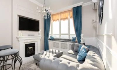 Sala de estar moderna con un mueble de televisor con chimenea: diseño, medidas y precios, consola de madera clara con chimenea eléctrica encendida y televisor montado encima.