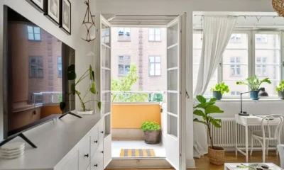 Mueble televisor blanco y madera: guía para elegir bien — salón moderno de estilo escandinavo con mueble televisor blanco y madera, televisor de pantalla plana, plantas y decoración minimalista.