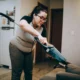 Mujer limpiando la aspiradora en la sala, ejemplo de cómo limpiar aspiradora