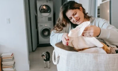 Mujer cargando ropa en una mini lavadora con vapor en el balcón de un pequeño apartamento — Mini lavadora con vapor: cómo elegirla y qué aporta de verdad
