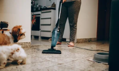 Persona utilizando un aspirador escoba friegasuelos en seco y humedo sobre el suelo duro de la cocina.