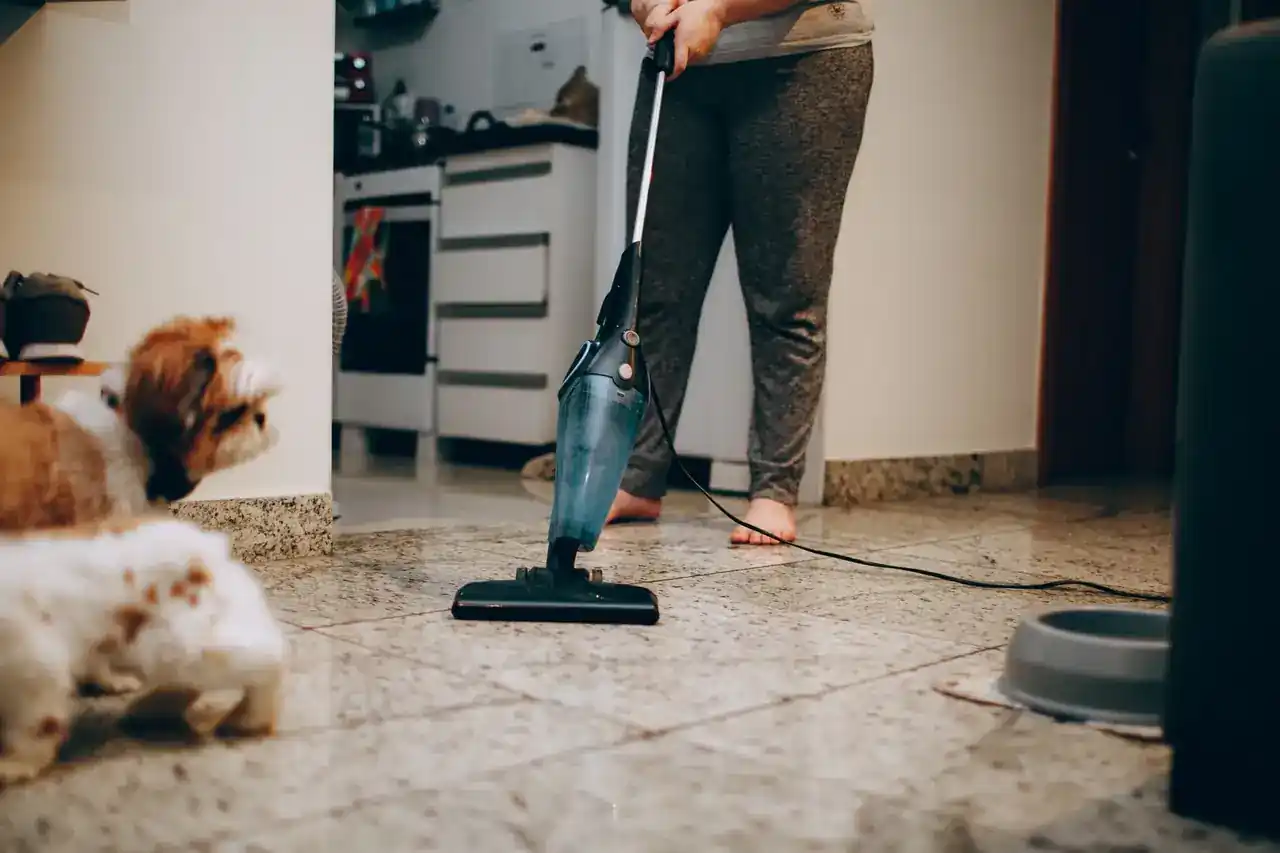 Persona utilizando un aspirador escoba friegasuelos en seco y humedo sobre el suelo duro de la cocina.